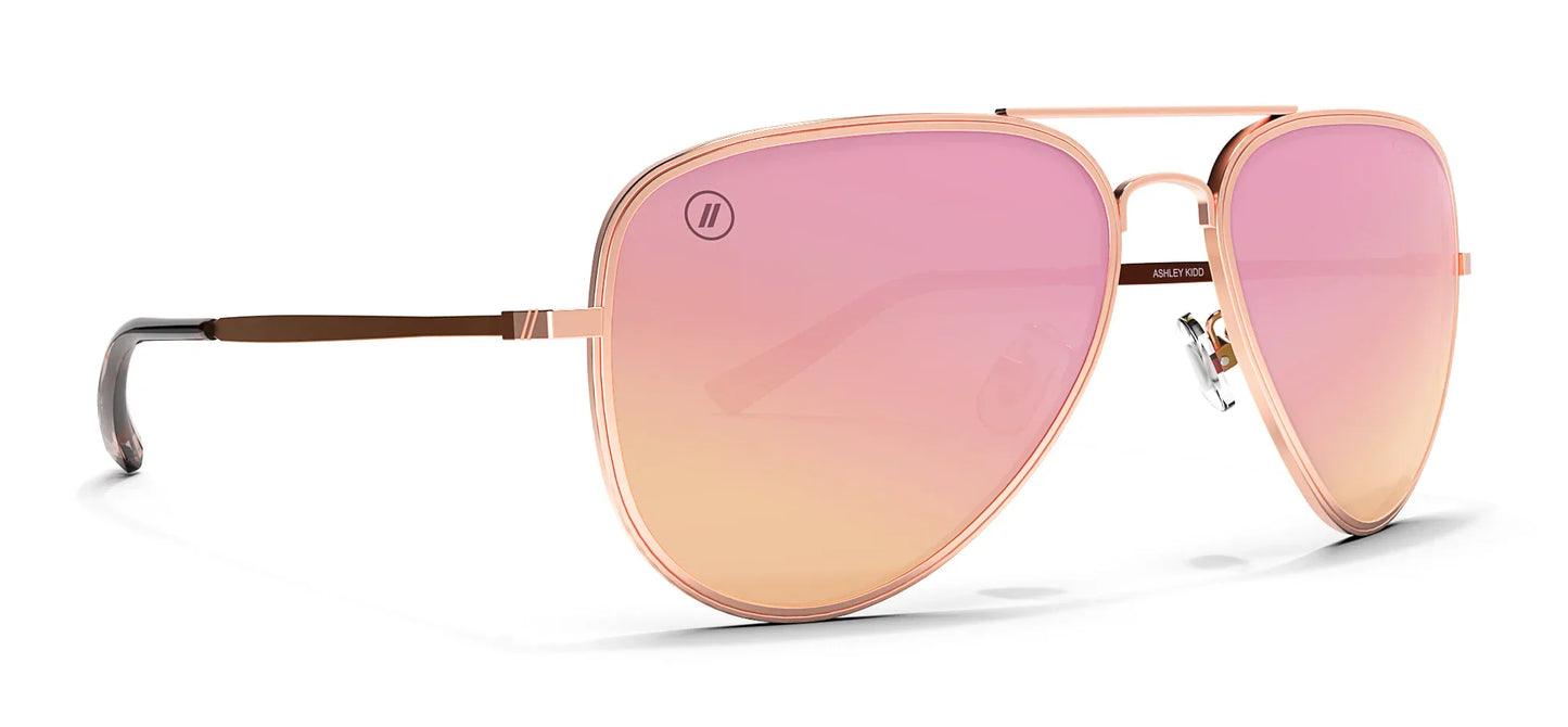 Aviator style Blenders sunglasses with rose gold frame and pink gradient lenses on a white background
