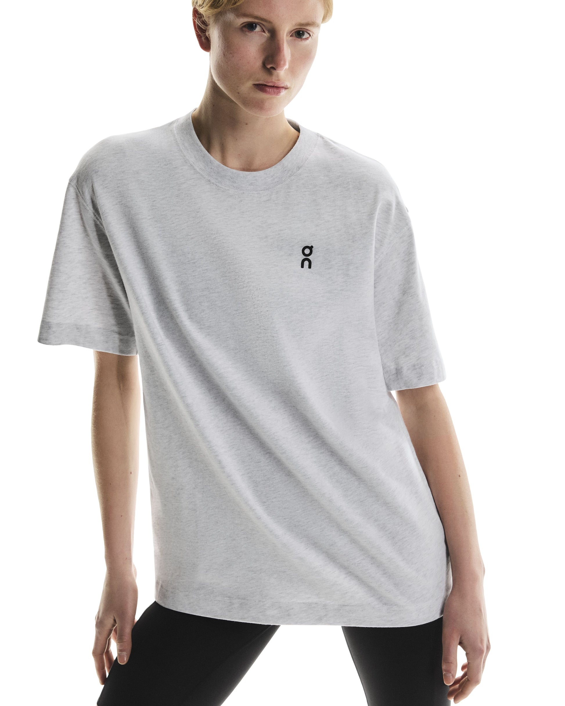 Person wearing a light gray t-shirt front view with a small logo on a white background